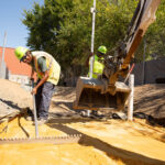 Flanigan crew using a mini excavator to level sand for storm water management