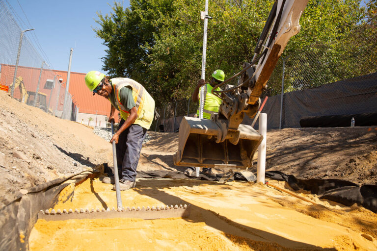 Flanigan crew using a mini excavator to level sand for storm water management