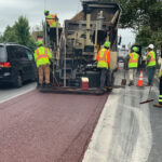 Flanigan paving crew using a paver to put down dark red asphalt on North Avenue for bus lanes